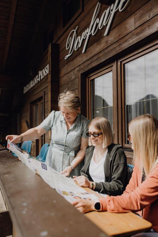 three women sitting at a table looking at a map at Hotel Dorfcafe Unken in Unken