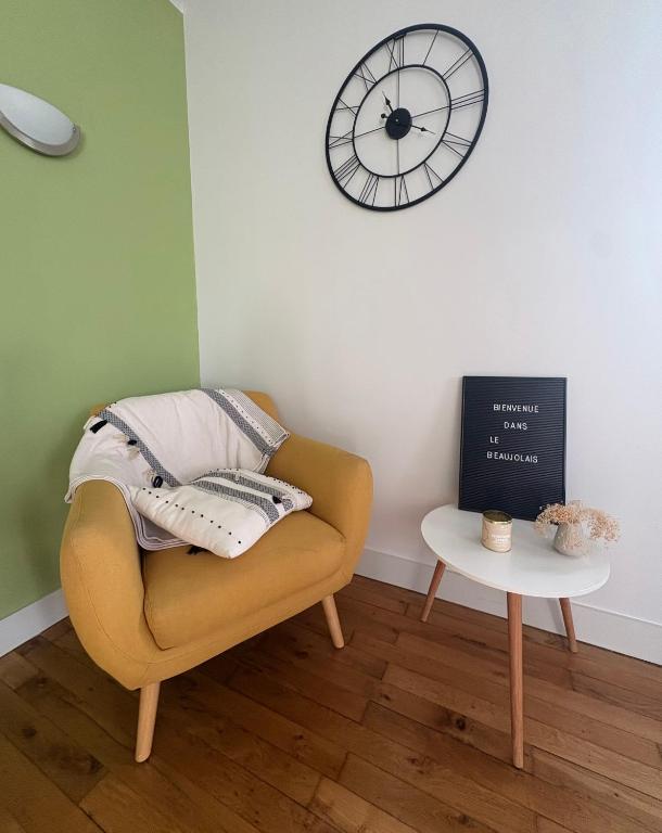 a living room with a chair and a clock on the wall at Bienvenue dans le Beaujolais in Le Perréon