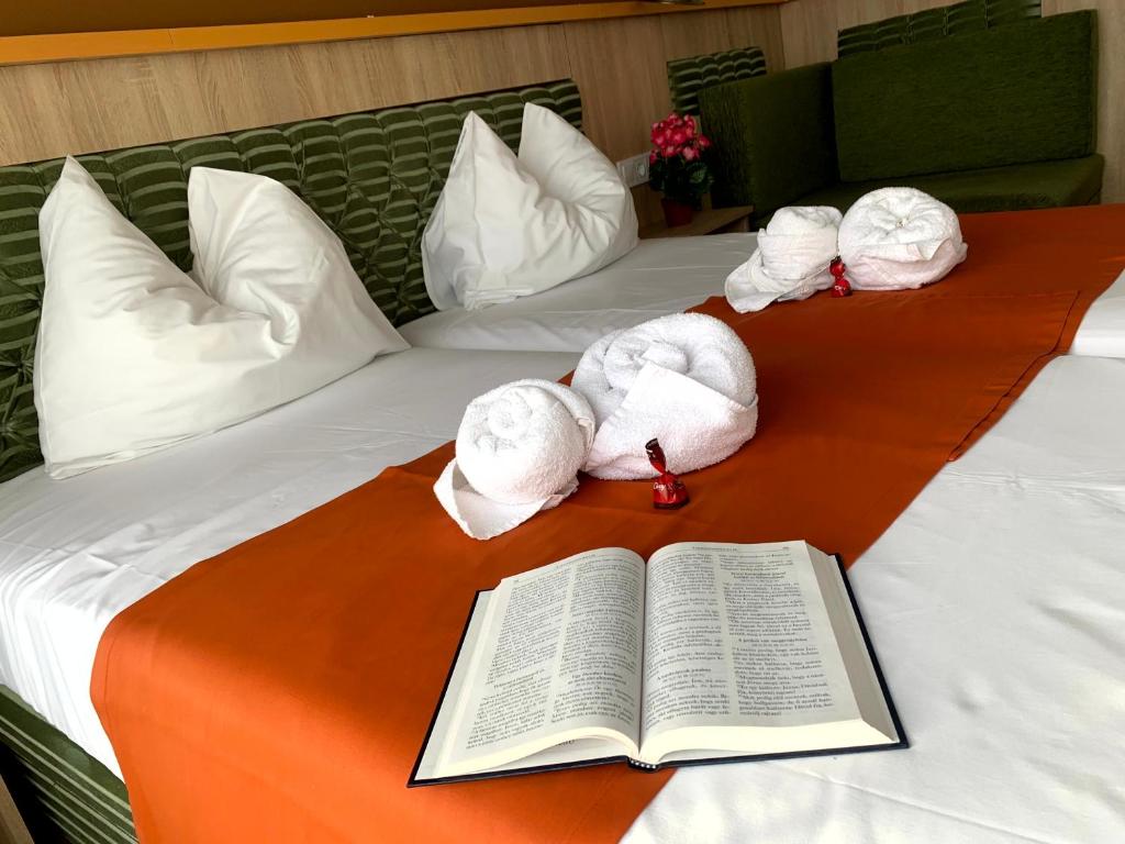 an open book on a bed with towels on it at Várfal Panzió és Wellness in Pécs