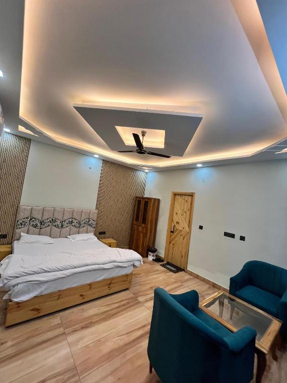 a bedroom with a bed and two blue chairs at Ekantam Mountain Cottages in Dehradun