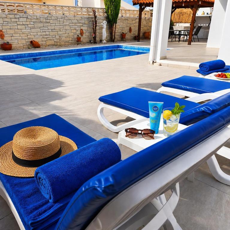 a patio with blue lounge chairs and a swimming pool at Villa Athena in Peyia