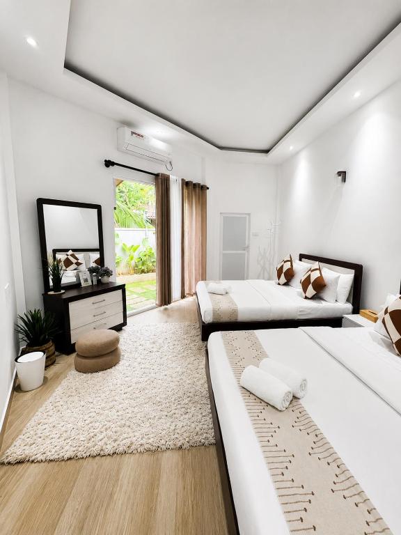 a white bedroom with two beds and a mirror at Cozy Vacation Home in Anuradhapura