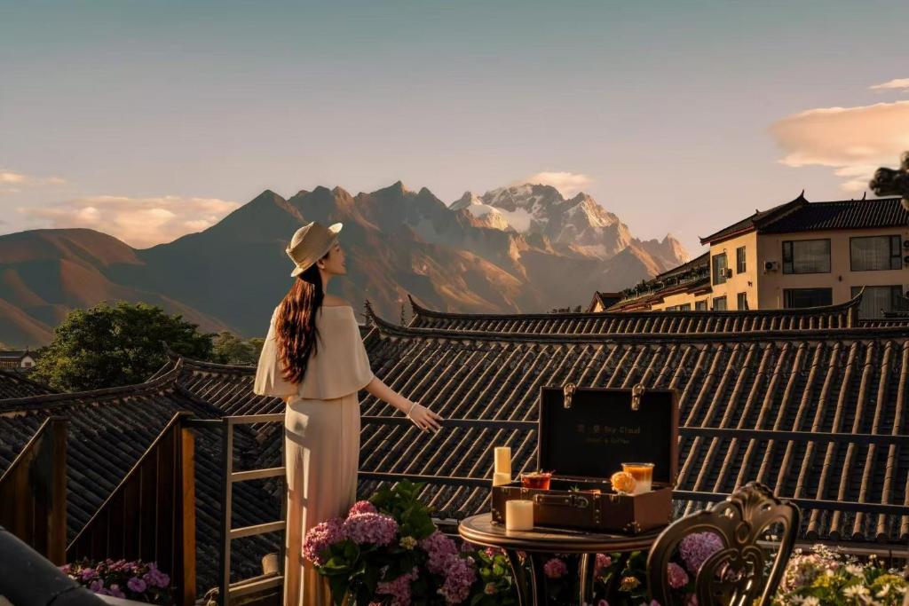 a woman standing on a balcony looking at the mountains at Yunman Sky Cloud Quiet Garden Guesthouse offers breakfast and afternoon tea with free airport shuttle services The hotel provides a platform for visiting the ancient city and Yulong snow in Lijiang