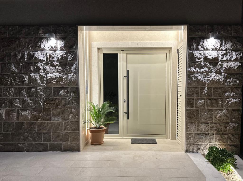 a white door with a potted plant on a brick wall at Stan Kumbor sa dvije spavace sobe in Kumbor