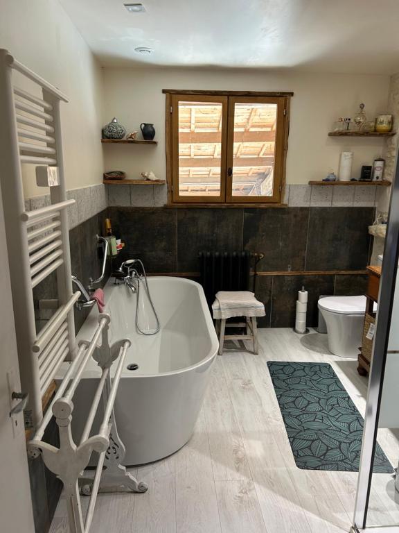 a bathroom with a bath tub and a toilet at Double chambres hôtes parentales in Damvix