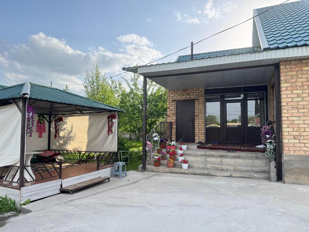 a house with a porch with potted plants in it at Hostel Hanysha in Kazarman