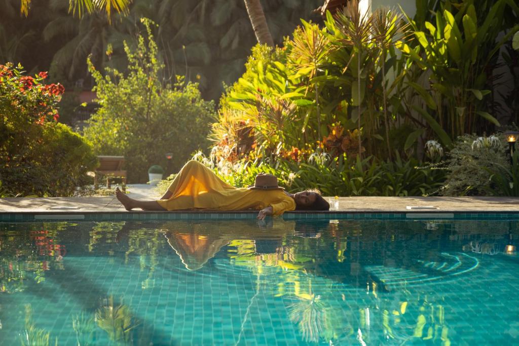 a man laying on the edge of a swimming pool at Pont Bleu Suites - boutique hotel -Riverside & Pool in Canacona