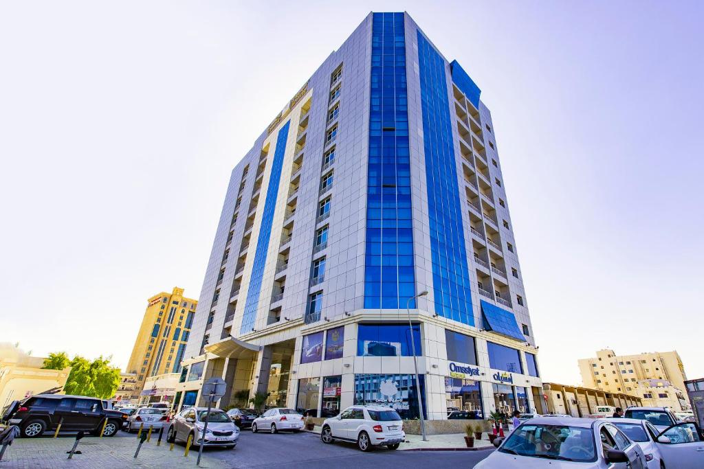 a tall building with cars parked in a parking lot at Imperial Suites Hotel in Doha