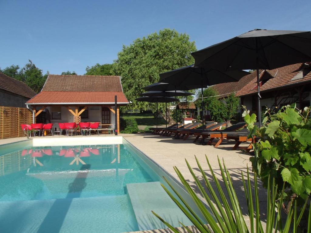 a swimming pool with tables and umbrellas and chairs at Remser Haus in Zalakaros
