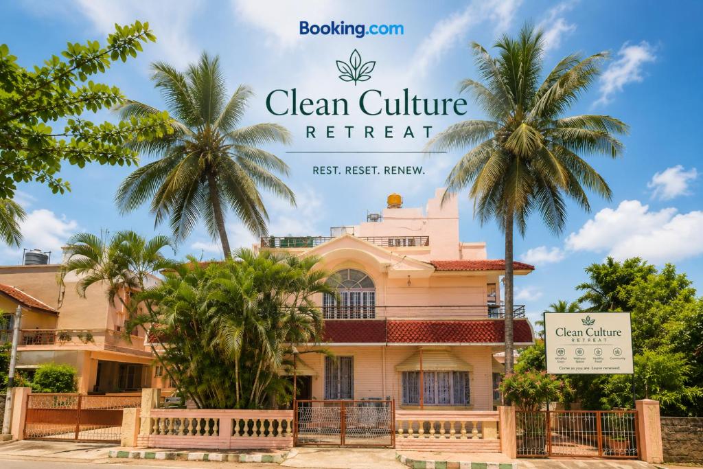a house with palm trees in front of it at Clean Culture Retreat in Mysore