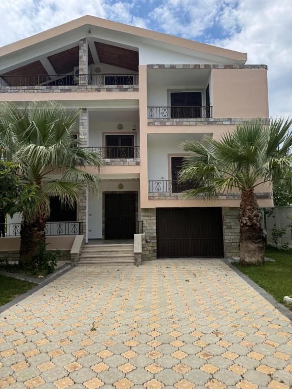 a house with two palm trees in front of it at Villa Velipoj in Velipojë