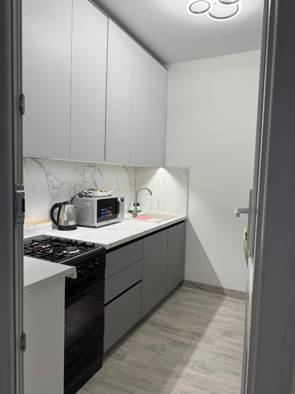 a white kitchen with a microwave and a stove at AeroHome Moldova- TAXI-PARKING ! in Chişinău