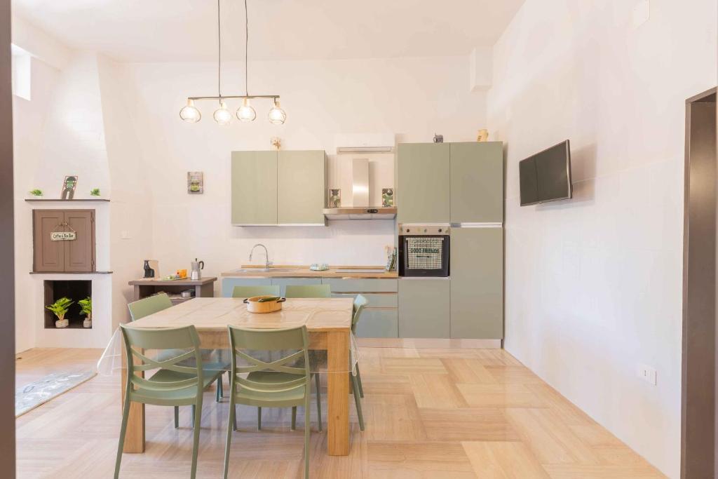 a kitchen with a table and some green chairs at Sweet Nonna Dora Corato - Casa con Parcheggio in Corato