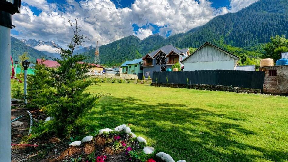 a yard with a house and a tree in a field at Pahadon Ka Ghar in Sonāmarg