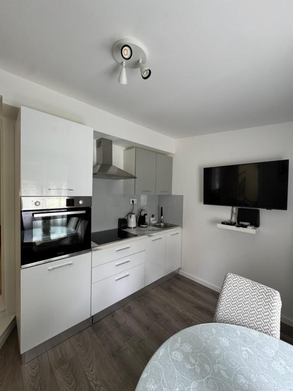 una cucina con mobili bianchi e una TV a schermo piatto di Mendula a Spalato (Split)