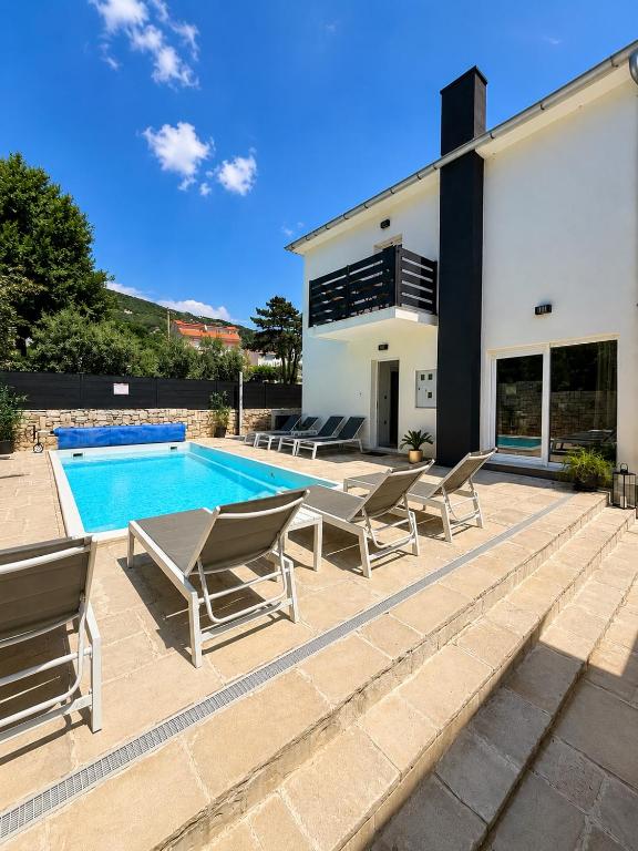 a villa with a swimming pool and lounge chairs at Vila Kety in Baška