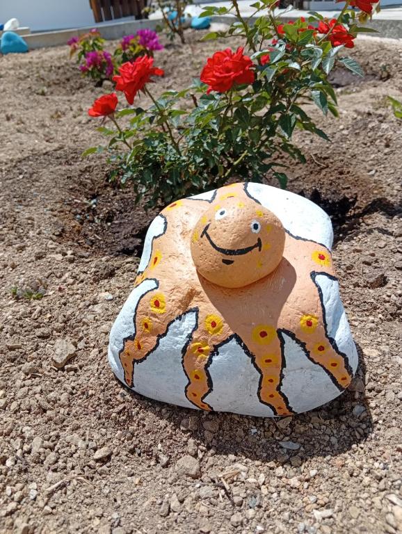 a rock with a dog painted on it next to flowers at Studios Αγκυρα in Livadi