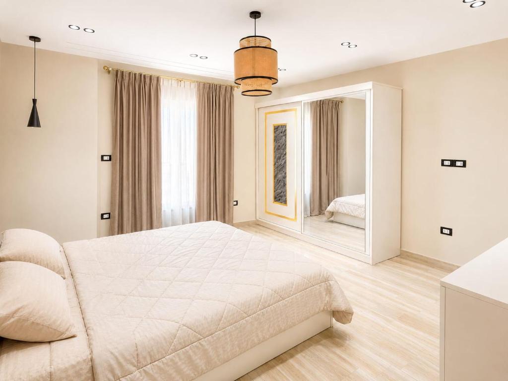 a white bedroom with a large bed and a mirror at Cyra gate Suncapital compound شقة في كامبواند صنكابيتال بوابة كايرا بالقرب in ‘Ezbet `Abd el-Ḥamîd