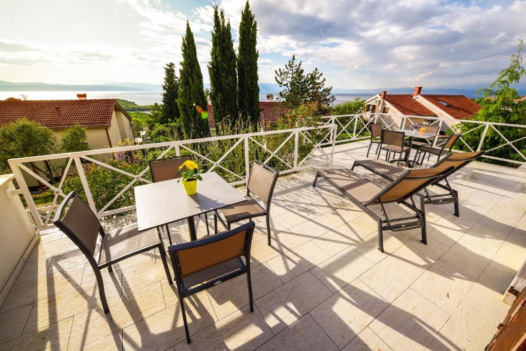eine Terrasse mit Tischen und Stühlen auf dem Balkon in der Unterkunft Apartmani Alice in Njivice