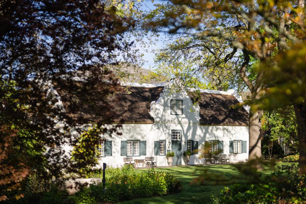 a white house with black windows and trees at Grande Provence in Franschhoek