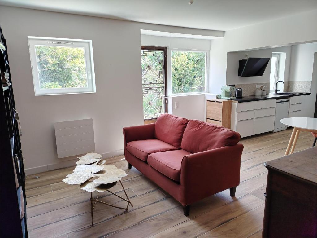 a living room with a red couch and a kitchen at La forge in Hinx