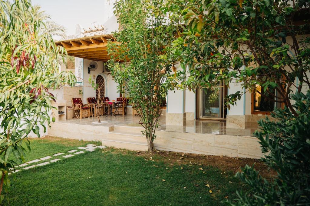 a house with a porch with chairs and trees at Tranquil Villa, private Pool, Garden, Wifi, Fayoum in Qaryat at Ta‘mīr as Siyāḩīyah