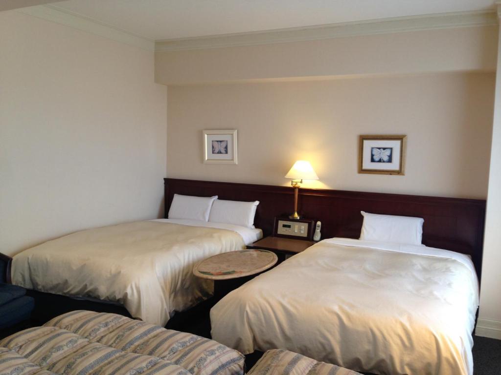 ein Hotelzimmer mit 2 Betten und einem Tisch in der Unterkunft Creston Hotel in Iwaki