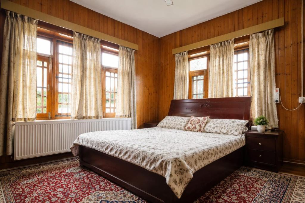 a bedroom with a bed and two windows at The Bilt farmhouse in Srinagar