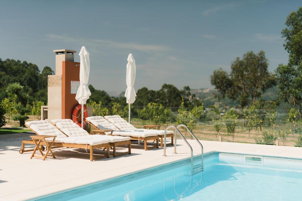 a pool with chairs and umbrellas next to at Souto Village - Douro Verde - by FERO in Maureles