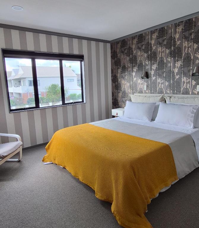 a bedroom with a large bed with a yellow blanket on it at Miro St Guest House in Mount Maunganui