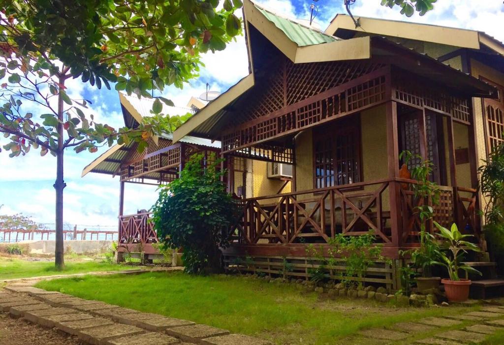 a wooden house with a porch and a tree at Pems Pension and Restaurant in Taytay