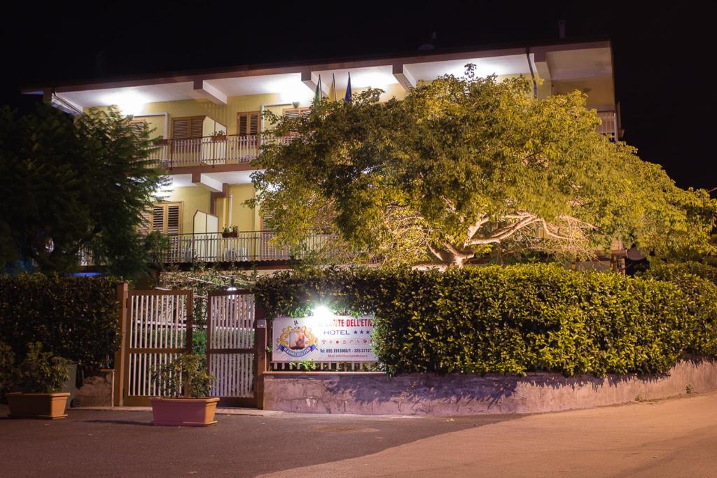 un edificio con un recinto e un albero di fronte ad esso di Hotel Il Conte Dell'Etna a Belpasso