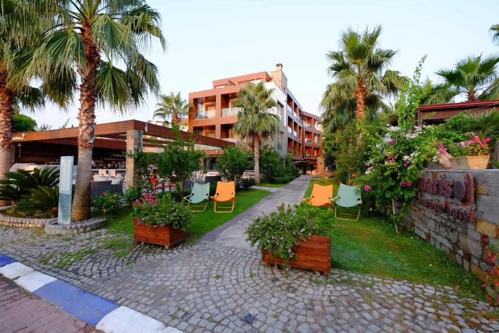 a resort courtyard with chairs and flowers and palm trees at Marisol Boutique Hotel in Gundogan