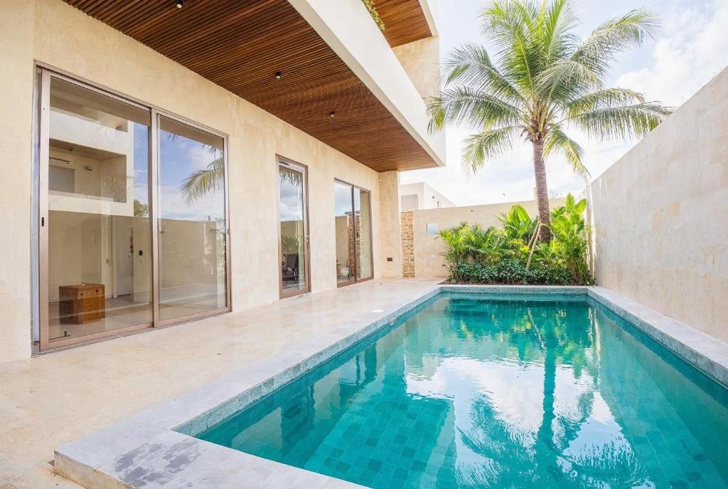 an empty swimming pool in a house with a palm tree at Surfside Uluwatu Resort in Uluwatu