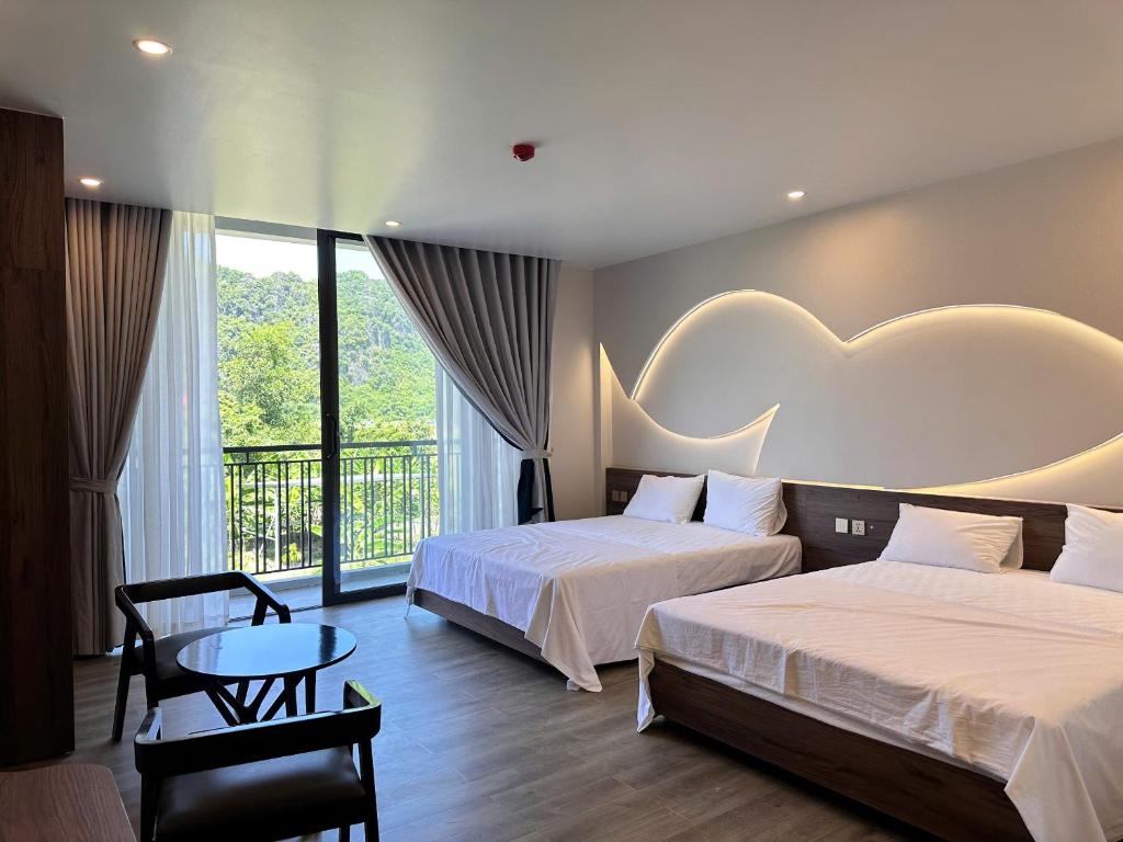 a hotel room with two beds and a table at Hidden Green Hotel Tam Coc in Vũ Lâm