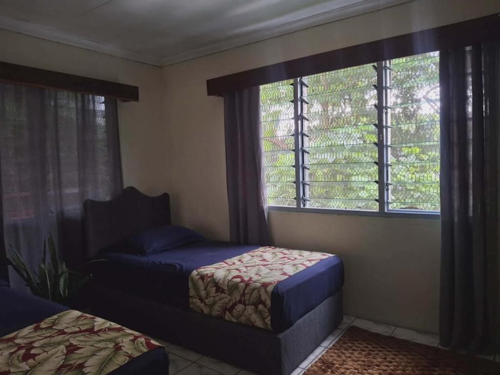 a bedroom with two beds and a window at Yaubula Bed and Breakfast Homestay in Nadi