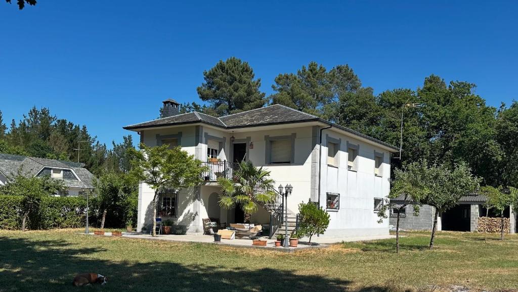 a white house with trees in the background at Refugio Rural A Revolta in Bergazo