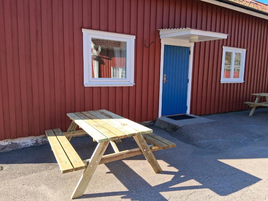 a wooden picnic table in front of a red building at Vandrarhem Varvet in Ellös