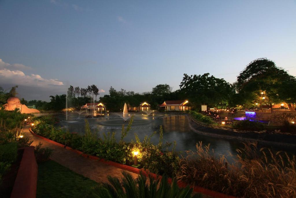 a view of a park at night with a fountain at Silent Shores Resort & Spa in Mysore
