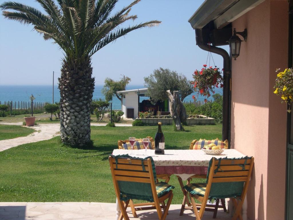 uma mesa com uma garrafa de vinho e uma palmeira em Elmani em Pozzallo