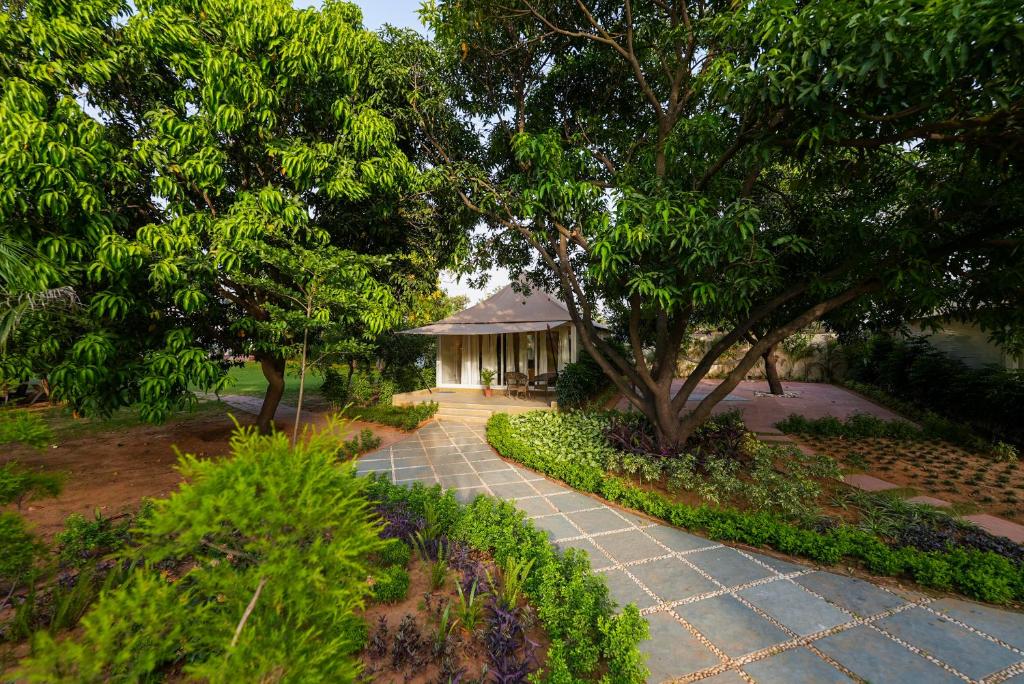 a walkway leading to a gazebo in a garden at Orchard At Sarai - Luxury Tent Villas, Swimming Pool, Large lawns, & Pet friendly in Gurgaon