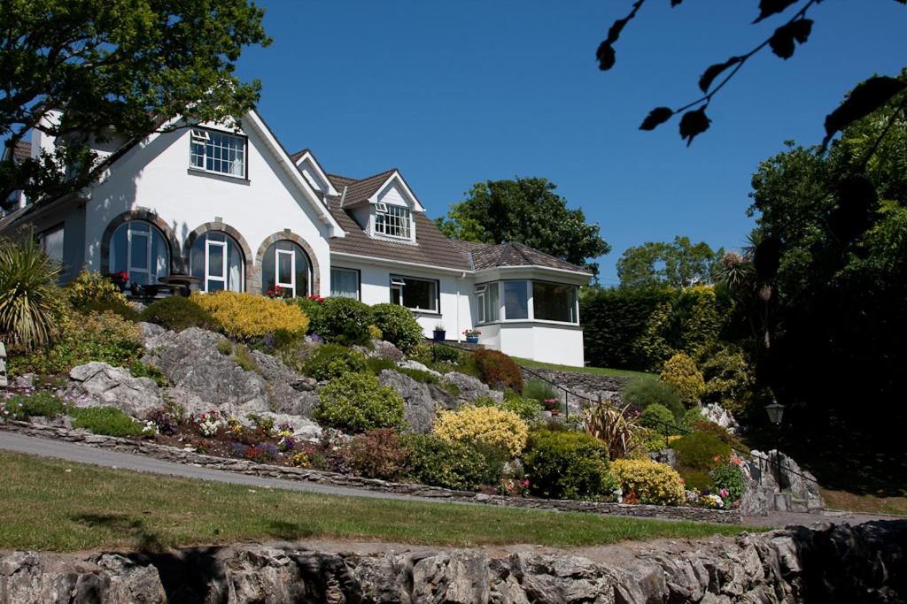 a white house on a hill with flowers in front at Rockcrest House in Kenmare