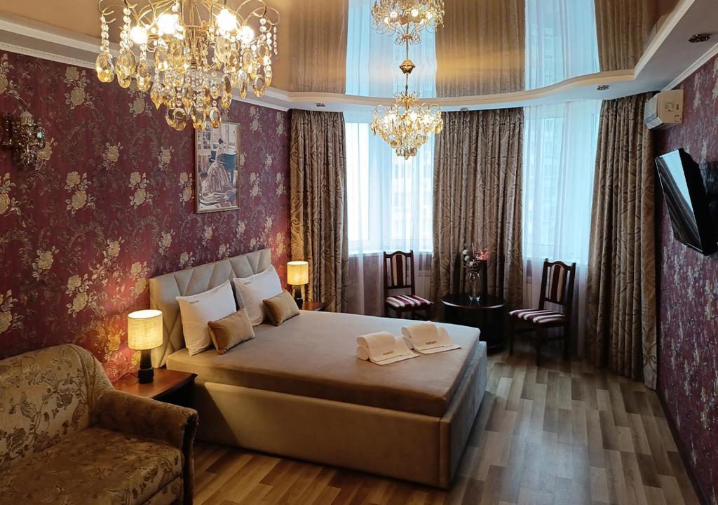 a bedroom with a bed and a couch and chandeliers at Poznyakoff Aparthotel in Kyiv
