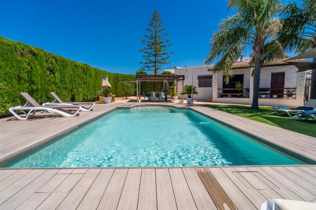 a swimming pool with a wooden deck and a house at Casa Rural Casita de la Cantera in La Lantejuela