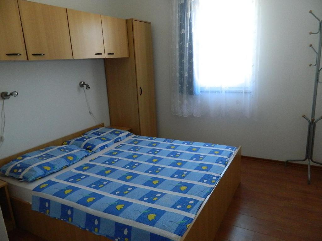 a bedroom with a bed with blue sheets and a window at Apartments Skender in Čižići