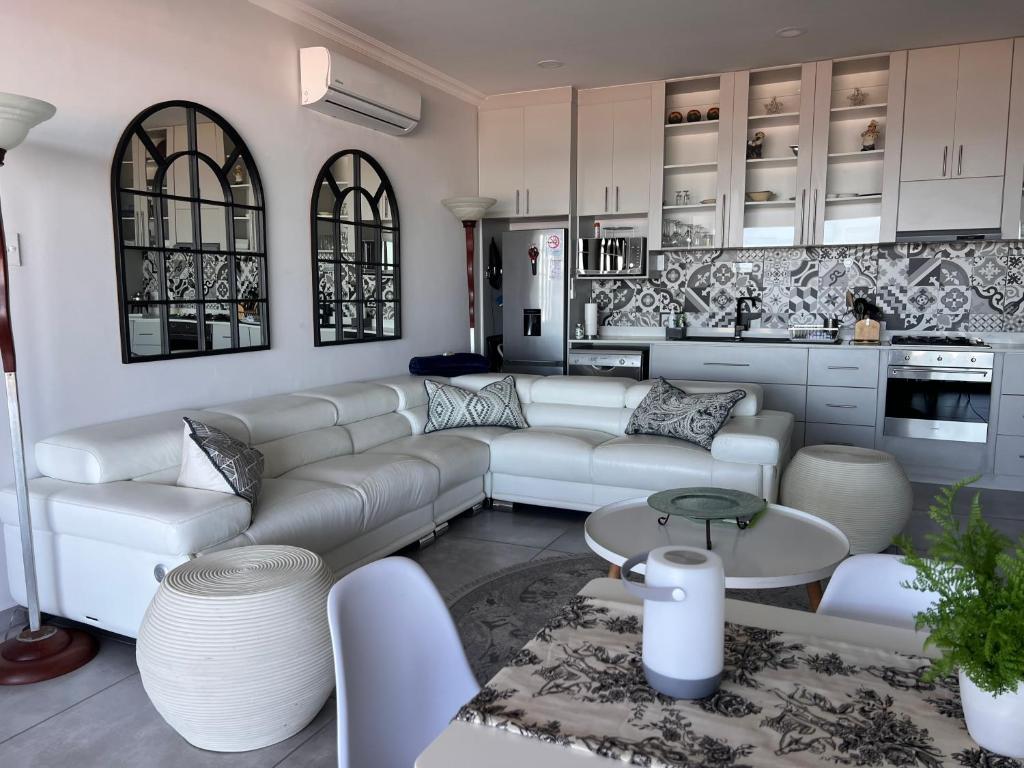 a living room with white furniture and a kitchen at Shelley Point On Sea in St. Helena Bay