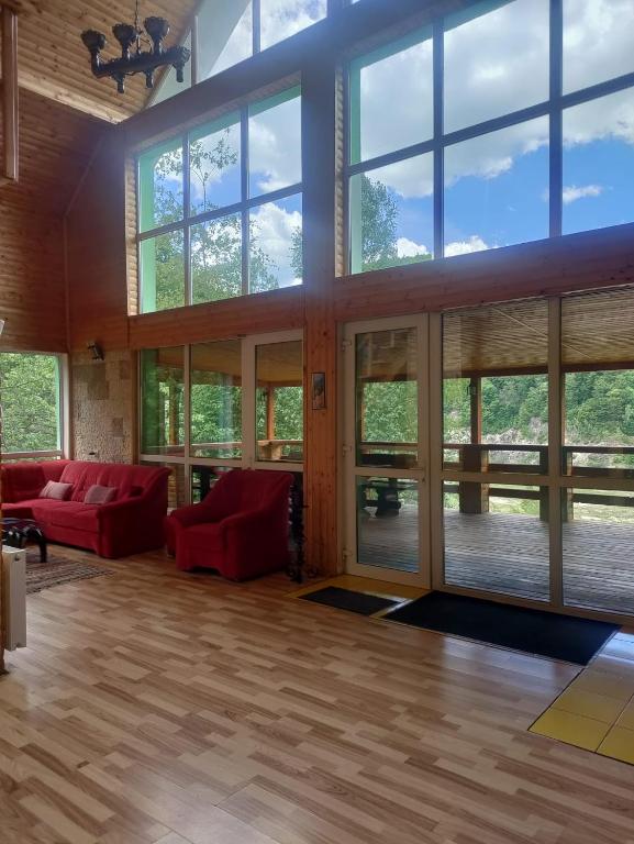 a large living room with red couches and large windows at Cabana 7 izvoare in Remeţi