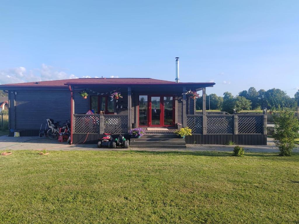 a blue house with a red door and a yard at Family vacations house in Tīnūži