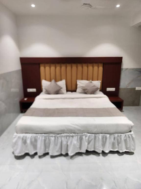 a bedroom with a large bed with a wooden headboard at Hotel Metro Palace L&B in Panvel