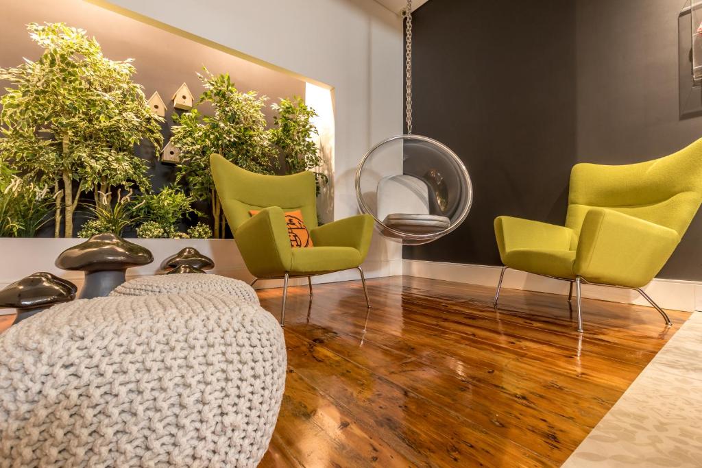a living room with yellow chairs and a wooden floor at RM The Experience - Small Portuguese Hotels in Setúbal